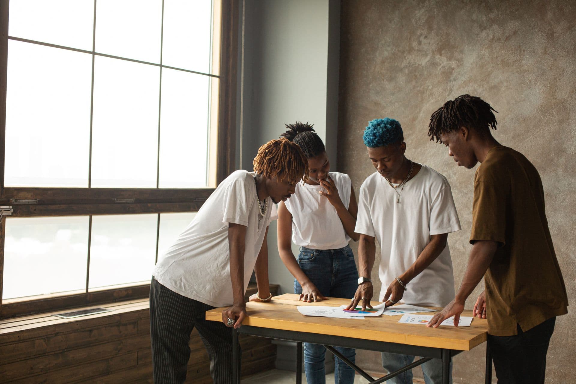 A small team leans over printed pages laid out on a studio table