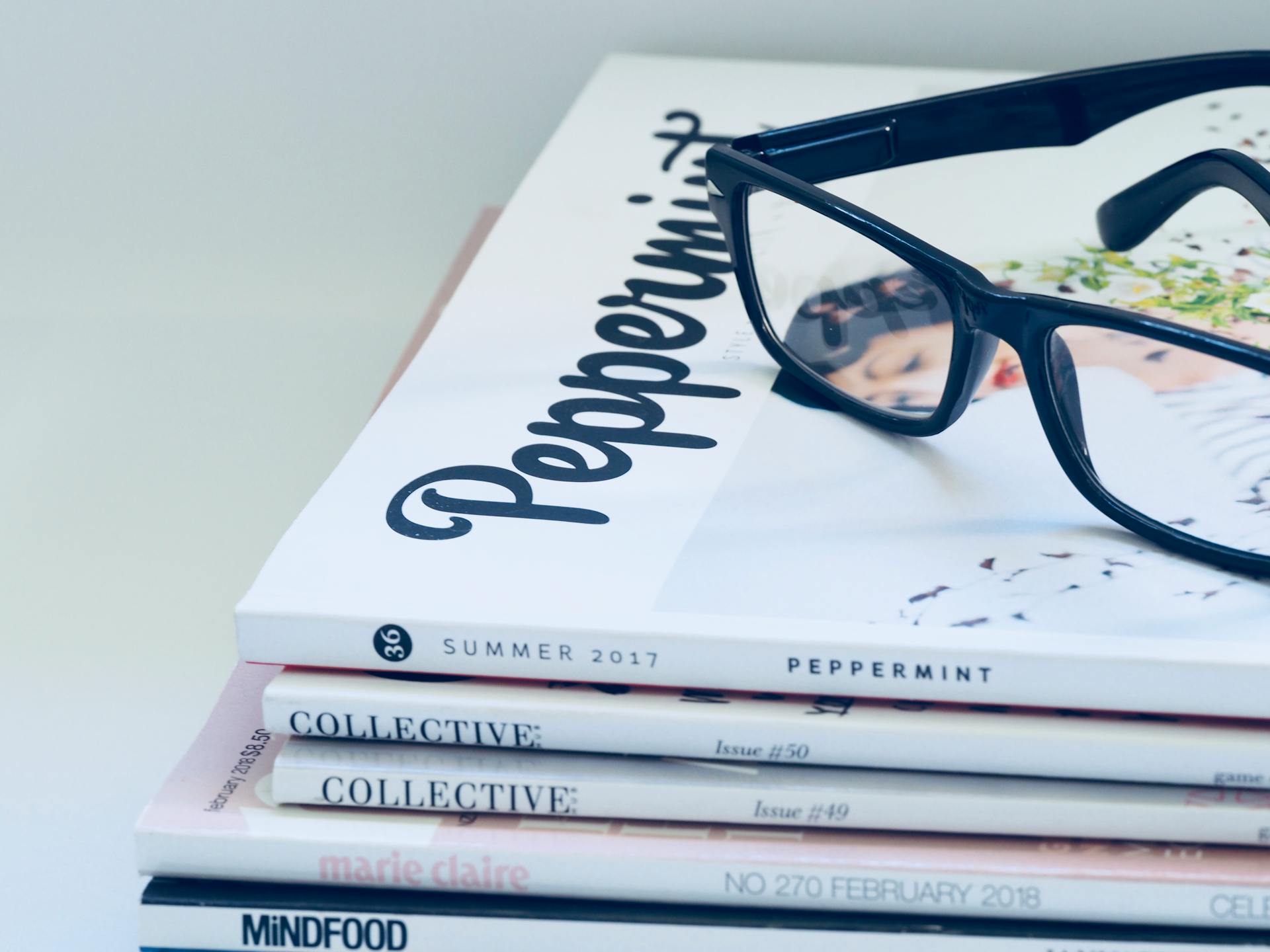 Magazine stack and glasses on a minimalist desk surface