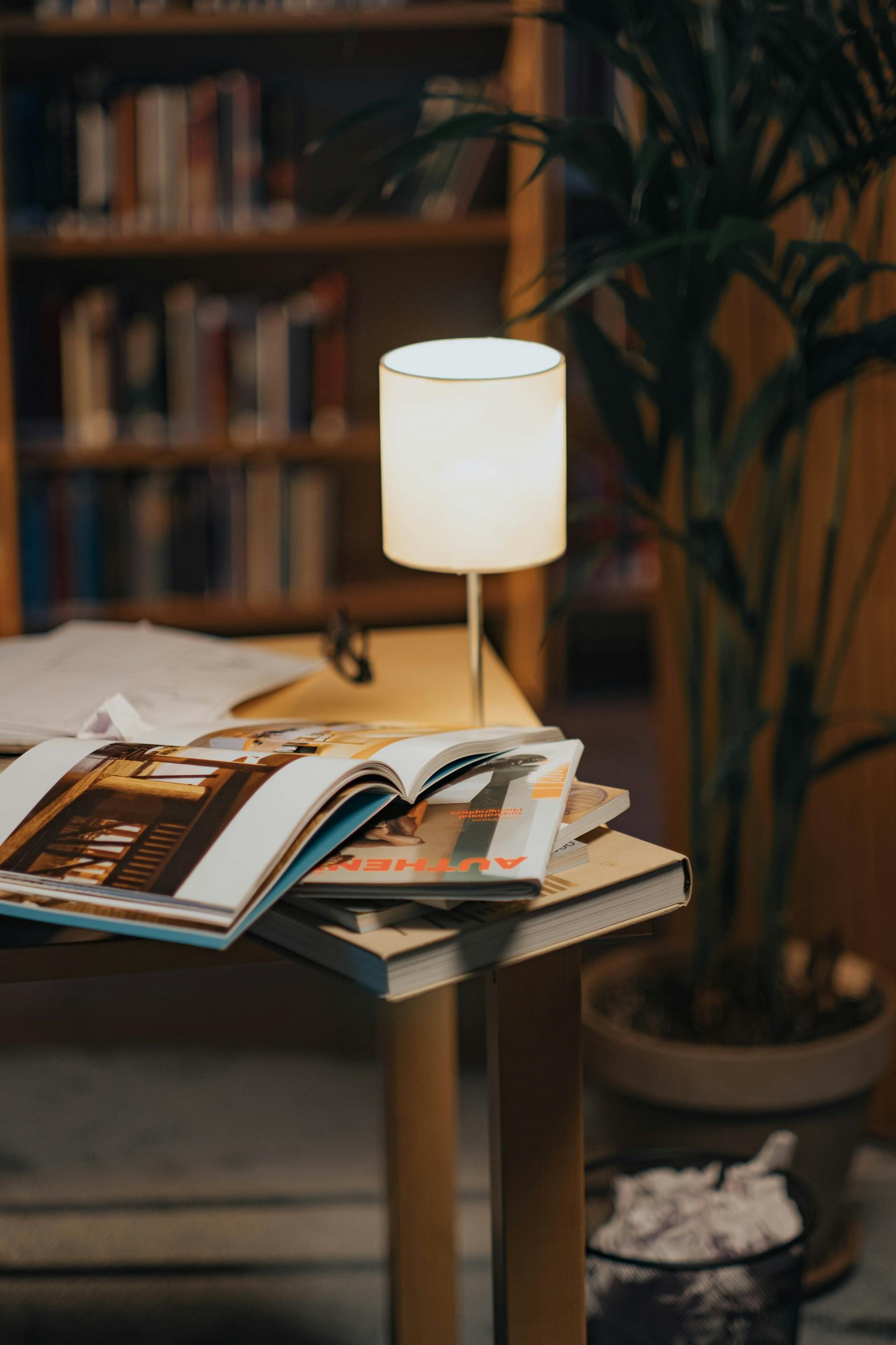 Curated magazine stack on a side table in a dimly lit lounge